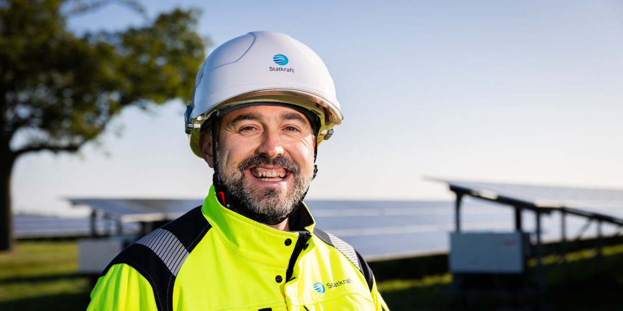 Homme portant un équipement de sécurité souriant avec des panneaux solaires en arrière-plan